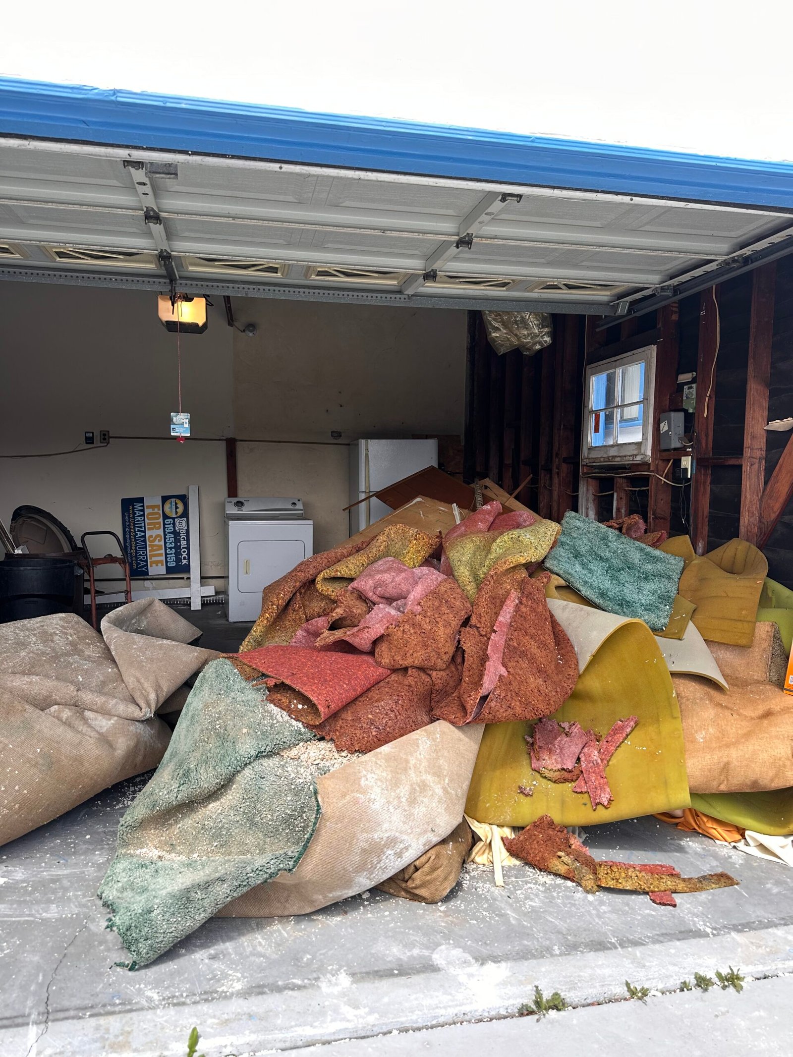 Garage Cleanouts A garage or carport with the door raised, revealing an interior space.