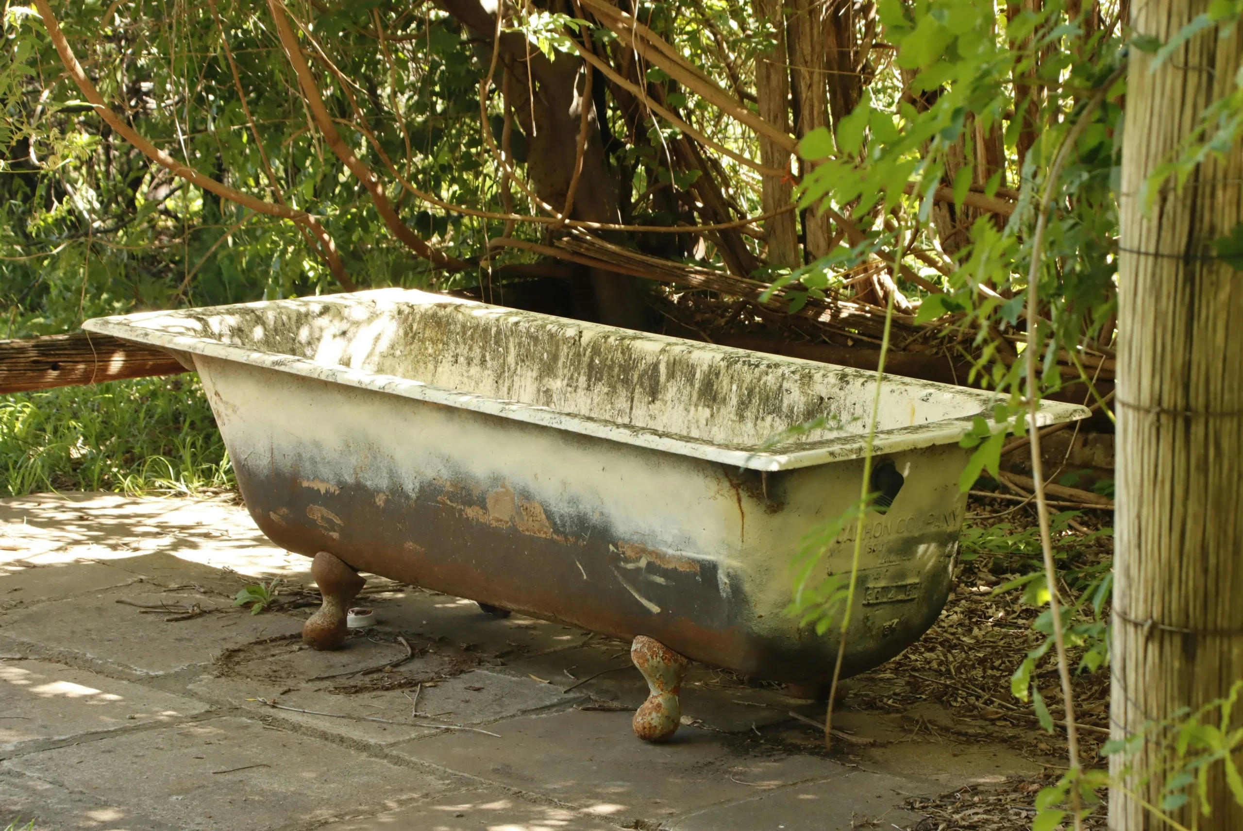 Hot Tub Removal An outdoor rural setting featuring a weathered clawfoot bathtub placed on uneven ground.